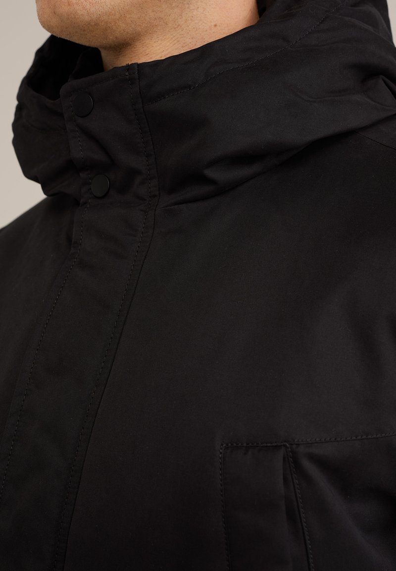 Schwarze Kapuzenjacke mit hohem Kragen, Druckknöpfen und einer Vordertasche, gefertigt aus glattem, mattem Stoff mit einem klaren Design.