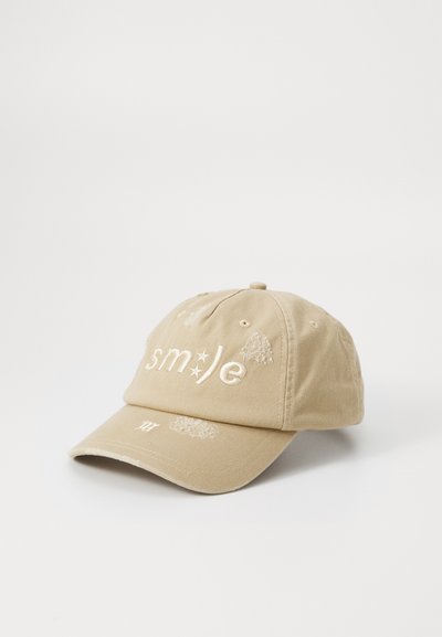 Beige cotton baseball cap featuring embroidered text "smile" in white, with subtle distress details on the front and visor.