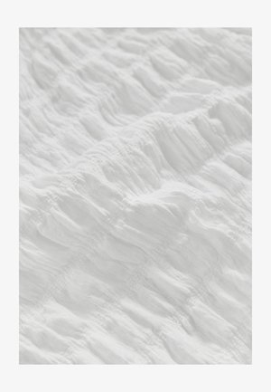 Țesătură albă texturată cu un design plisat, având secțiuni ridicate și un aspect moale, potrivită pentru lenjerie de pat sau scopuri decorative.