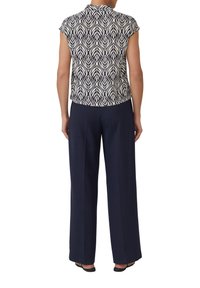 Top à manches courtes avec un motif de feuilles bleu marine, associé à un pantalon large bleu marine, présentant une texture lisse et un design de col classique.