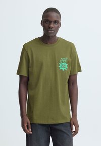 Olijfgroene katoenen T-shirt met korte mouwen, voorzien van een turquoise "FRESH! BLEND" afbeelding op de linkerborst. Ronde hals en een losse pasvorm.