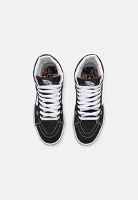 Baskets montantes noires à lacets blancs, avec des motifs floraux sur la doublure intérieure. Construites en daim. Bout arrondi et semelle en caoutchouc.