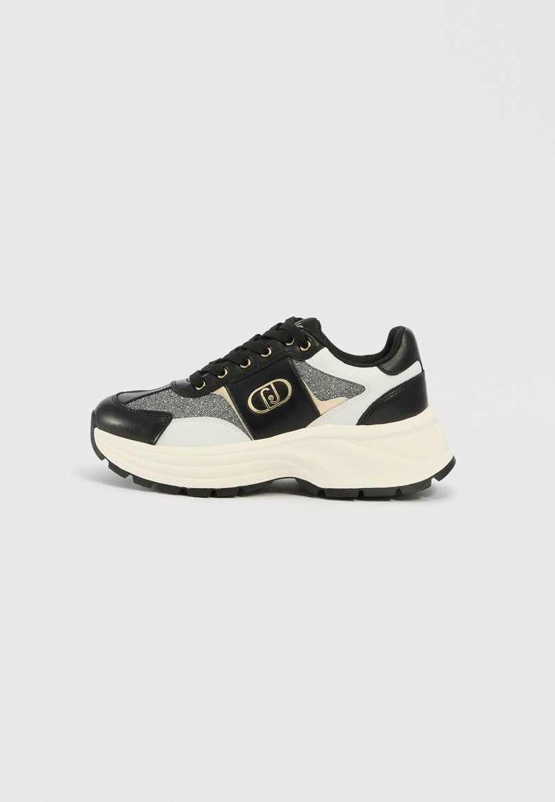 Schwarzer und weißer Sneaker mit einem strukturierten Obermaterial, glatten Lederakzenten, einer klobigen weißen Zwischensohle und goldenen Details an der Seite.