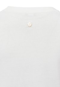 Witte gebreide trui met een ronde halslijn, voorzien van een klein gouden embleem op de achterkant. De stof lijkt glad en licht van gewicht te zijn.