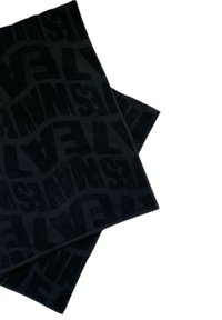 Tessuto nero con un motivo testurizzato che presenta testo audace e stilizzato. Il materiale appare morbido con una finitura in peluche, piegato in strati.