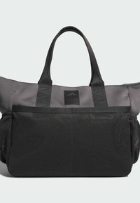 Sivá a čierna taška na rameno s dvoma rukoväťami a veľkou čiernou sieťovanou vreckou na prednej strane na jednoduchom svetlom pozadí.