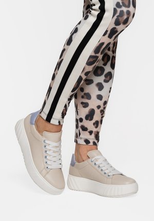 Beige platform-sneakers med hvide snørebånd, båret med beige leopardmønstrede leggings med sorte og hvide sidelister.