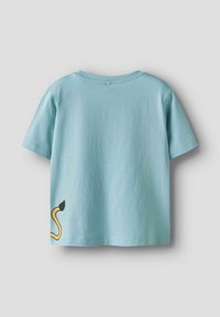 Lysblå bomulds T-shirt med korte ærmer, prydet med et sort og gult slangemotiv på den nederste venstre side. Klassisk rund halsudskæring.