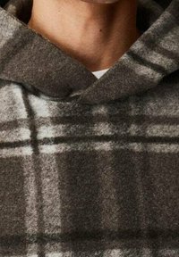 Sudadera con capucha de cuadros grises con una tela suave y texturizada. Cuenta con una capucha grande y patrones de cuadros superpuestos en tonos más oscuros y más claros.