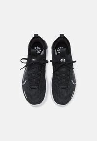 Chaussures de sport noires avec une tige texturée, des lacets et un logo blanc sur le côté. Contient une semelle rembourrée et un tirant au talon pour le soutien.