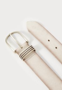 Svijetlo bež kožni remen sa srebrnom kopčom i više petlji, prikazuje šiljasti kraj i dvije rupe za podešavanje na bijeloj pozadini.