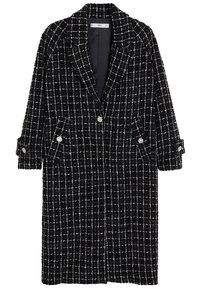 Longue veste à carreaux noir et blanc avec un col cranté, deux poches latérales et des poignets boutonnés. Tissu texturé avec une forme structurée.