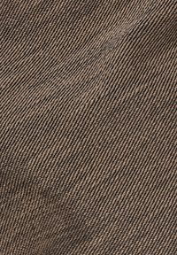 Hnědý textil s diagonálním žebrovaným vzorem, má hladkou strukturu a měkký povrch. Látka působí odolně a mírně leskle.