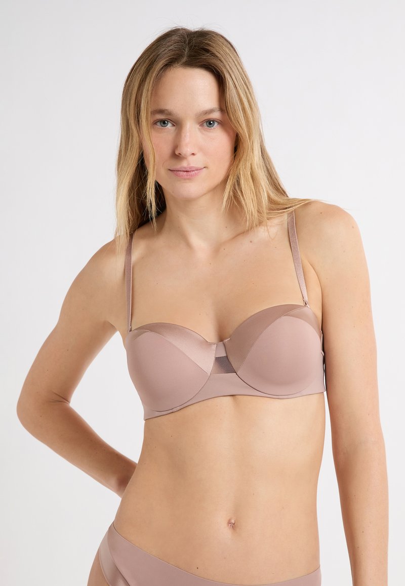 Reggiseno in morbido tessuto color nudo con finitura liscia, coppe sagomate e spalline sottili regolabili, con dettagli in mesh al centro.