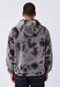 Grijze fleece hoodie met een getextureerd, zacht oppervlak, voorzien van een zwart spetterpatroon, een capuchon en een ontspannen pasvorm.