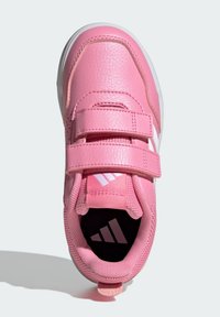 Różowy but sportowy z syntetyczną cholewką ze skóry, podwójnymi paskami na rzepy, siateczkowymi detalami oraz białą gumową podeszwą z logo wewnątrz.