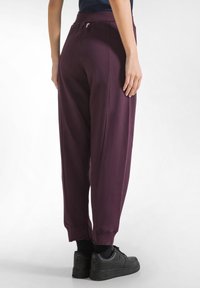 Vinröda sweatpants med avslappnad passform, elastisk midja och muddar. Matchas med svarta sneakers. Slät, mjuk tygkvalitet.