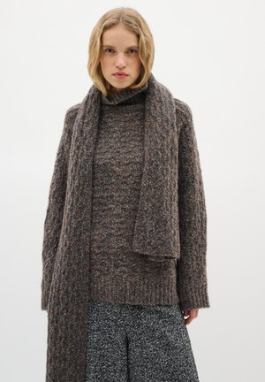 Brown knitted sweater with a high neck, paired with a matching scarf. Textured fabric and relaxed fit. Below, a skirt with a herringbone pattern.