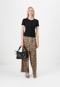 Svart tettsittende T-skjorte med kort erme, leopardmønstret vide bukser, svart vevd håndveske, og beige spisse hæler. Enkel bakgrunn.