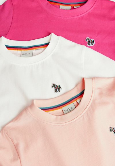 Tre T-shirt: rosa, bianca e rosa chiaro. Ognuna presenta un piccolo logo di zebra ricamato e una banda collo a strisce colorate.