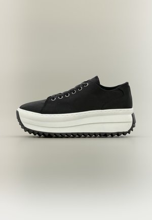 Sneaker nera a taglio basso con suola piattaforma bianca spessa e suola esterna nera zigrinata, vista laterale su sfondo neutro.
