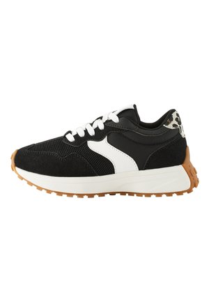 Zapatilla en blanco y negro con materiales de malla y ante, suela acolchonada y un detalle estampado en el talón. Suela exterior de goma para mejor tracción.