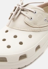 Μπεζ παπούτσι χωρίς κορδόνια με μεγάλες οπές αερισμού, δερμάτινο επάνω μέρος με κορδόνια και ανάγλυφη άκρη σόλας για άνεση και αναπνευσιμότητα.