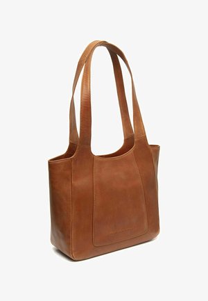 Sac cabas en cuir marron avec deux longues poignées d'épaule et une poche avant, debout sur un fond blanc.