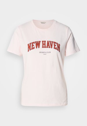 Jasnoróżowa bawełniana koszulka z napisem "NEW HAVEN" dużymi czerwonymi literami, z "SPORTS CLUB" poniżej. Krótkie rękawy i okrągły dekolt.