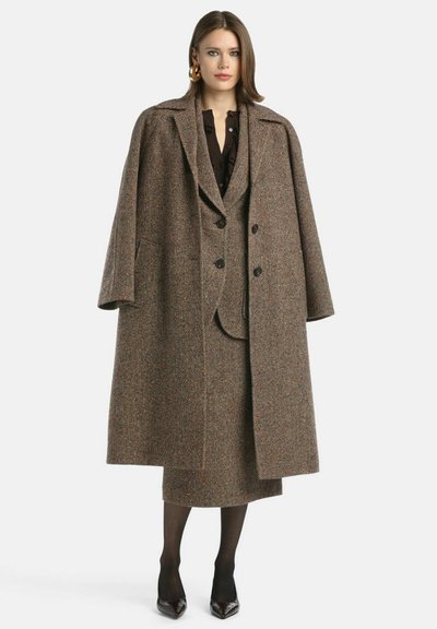 Houndstooth takkivilla takki, jossa on ylisuuri muotoilu, kaksirivinen etu, leveät hartiat ja suuret napit. Tummanruskea väri.