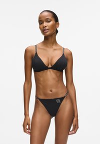 Zwart bikiniset van gladde stof, bestaande uit een driehoekige bh en een string. Dunne bandjes met contrasterende accenten op de band.