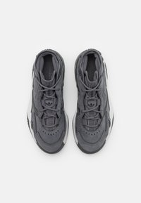 Grå sportskor med en kombination av strukturerad mocka och mesh, med vadderad krage, rund tå och gummisulor. Designen inkluderar snören och ventilationshål.