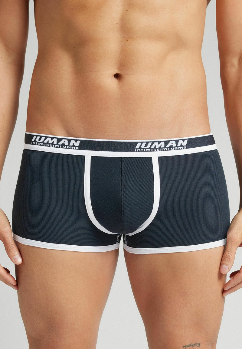 Ciemnoniebieskie jaskółki z prążkowanej tkaniny z białym pasem z napisem "Iuman" i "intimissimi uomo". Długość do połowy uda, dopasowane.