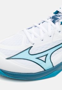 Zapatilla deportiva blanca con parte superior de malla texturizada, acentos turquesa y un diseño curvado. Detalles en azul a lo largo del costado añaden interés visual.