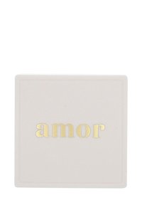 Posavasos de cerámica en un suave tono rosa, con un borde elevado, que presenta la palabra "amor" en foil dorado. Textura suave, forma cuadrada.
