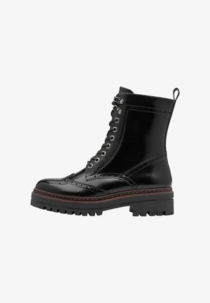 Stivale alla caviglia in pelle nera con design a brogue, con lacci frontali, suola spessa e cuciture decorative. Presenta un manico sul retro.