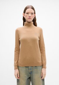 Sweter w kolorze camel z golfem, wykonany z miękkiego materiału dzianinowego, z dopasowanymi długimi rękawami i prążkowanymi mankietami, z małym logo na piersi.
