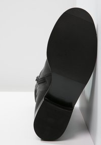 Czarne skórzane buty z fakturowaną gumową podeszwą. Posiadają zamek błyskawiczny z boku oraz gładkie wykończenie, zaprojektowane z myślą o trwałości i komforcie.