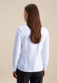 Witte langarmshirt met een gestructureerd ontwerp, voorzien van een rechte snit, met knoopmanchetten en rugplooien. Glad textieloppervlak.
