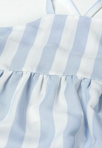 Top de tejido ligero con rayas verticales azules y blancas, con un detalle fruncido a lo largo de la costura y tirantes delgados ajustables.