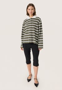 Striped long-sleeve top in olive green and white, collar detail; paired with fitted black capri pants and black pointed flats.