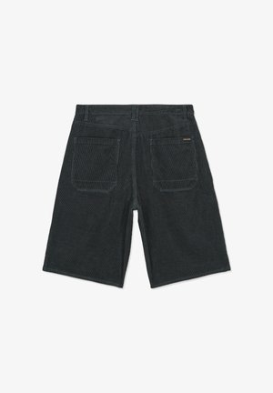 Shorts en velours côtelé noir avec deux poches arrière et une petite étiquette du logo Volcom sur la poche droite, posés à plat sur un fond blanc.