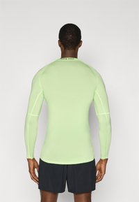 Αθλητική μπλούζα μακριάς μανίκας σε ανοιχτό πράσινο χρώμα, με λείο, ελαστικό ύφασμα και εφαρμοστή γραμμή, με λογότυπο "NIKE PRO" στο λαιμό.