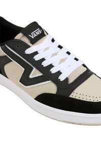 Black, beige, and white sneaker with a textured canvas upper, leather accents, and white laces. Features a prominent logo and perforated toe.