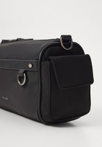 Borsa in tessuto nero con forma rettangolare, dotata di una tasca frontale con patta, accessori in argento e una maniglia superiore per un facile trasporto.