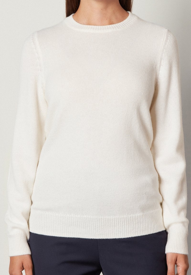 Maglione bianco lavorato a maglia con scollatura rotonda, maniche lunghe e polsini e orlo a costine. Tessuto liscio con dettagli di cucitura sottili.