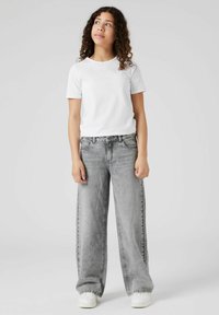 Jeans gri cu picioare largi, cu o finisare uzată, asortați cu un tricou alb simplu cu mânecă scurtă și adidași albi. Design simplu, fără modele.