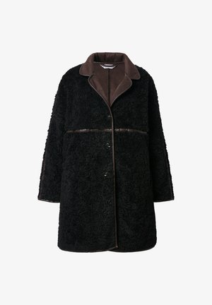Manteau en peluche noir avec un col en daim brun, fermeture à boutons et tissu extérieur texturé. Les manches et l'ourlet sont légèrement surdimensionnés.