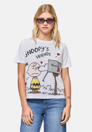 Woman in sunglasses and jeans wears a white t-shirt featuring Charlie Brown and Snoopy at a mailbox, with "Snoopy's Friends" text.