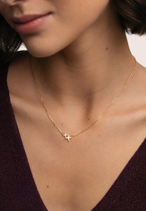 Collar de oro con una cadena delicada y un colgante geométrico con pequeños acentos de diamantes. Superficie texturizada y diseño intrincado.